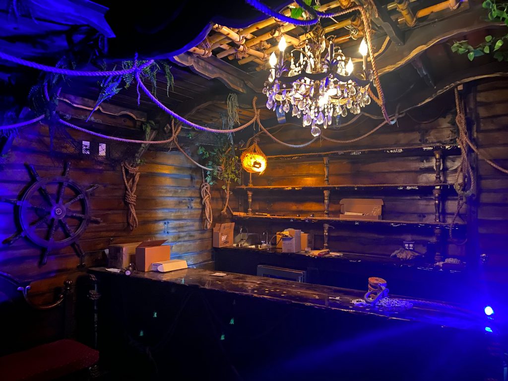 nautic themed dark lit bar by a large chandelier