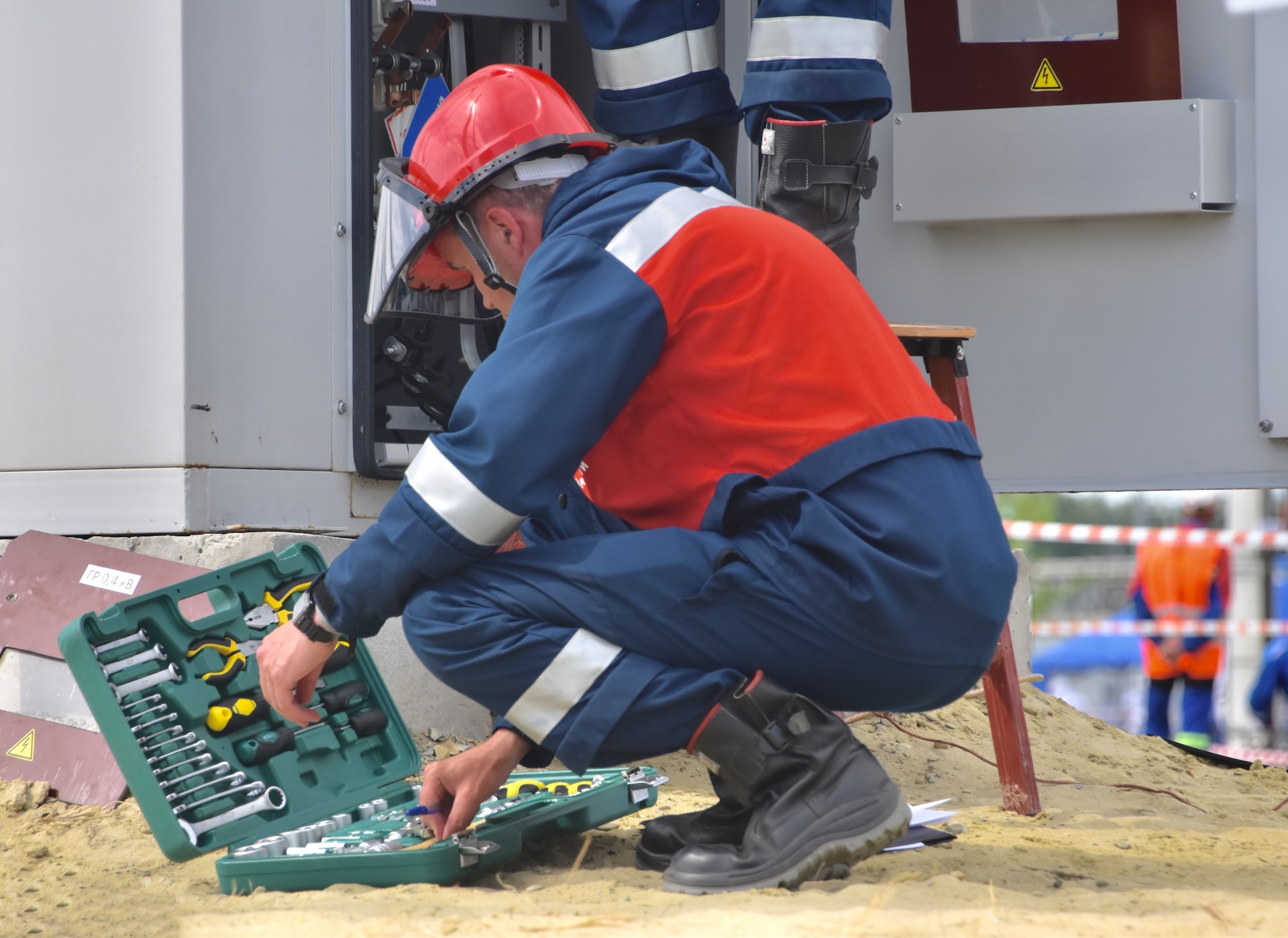 Man opening a tool kit on the ground in safety gear