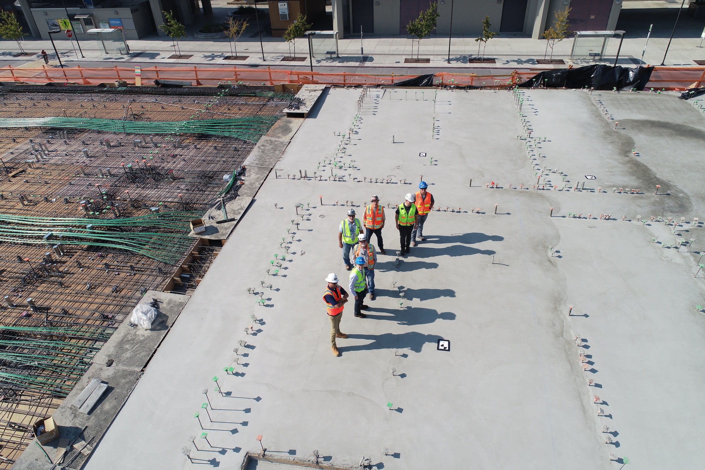 People Standing on a Rooftop in High Visibility Jackets and Hard Hats