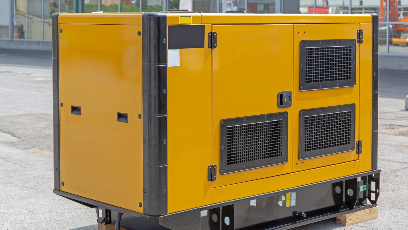 A Large, Yellow Commercial Generator Sits on the Ground in Front of a Building.